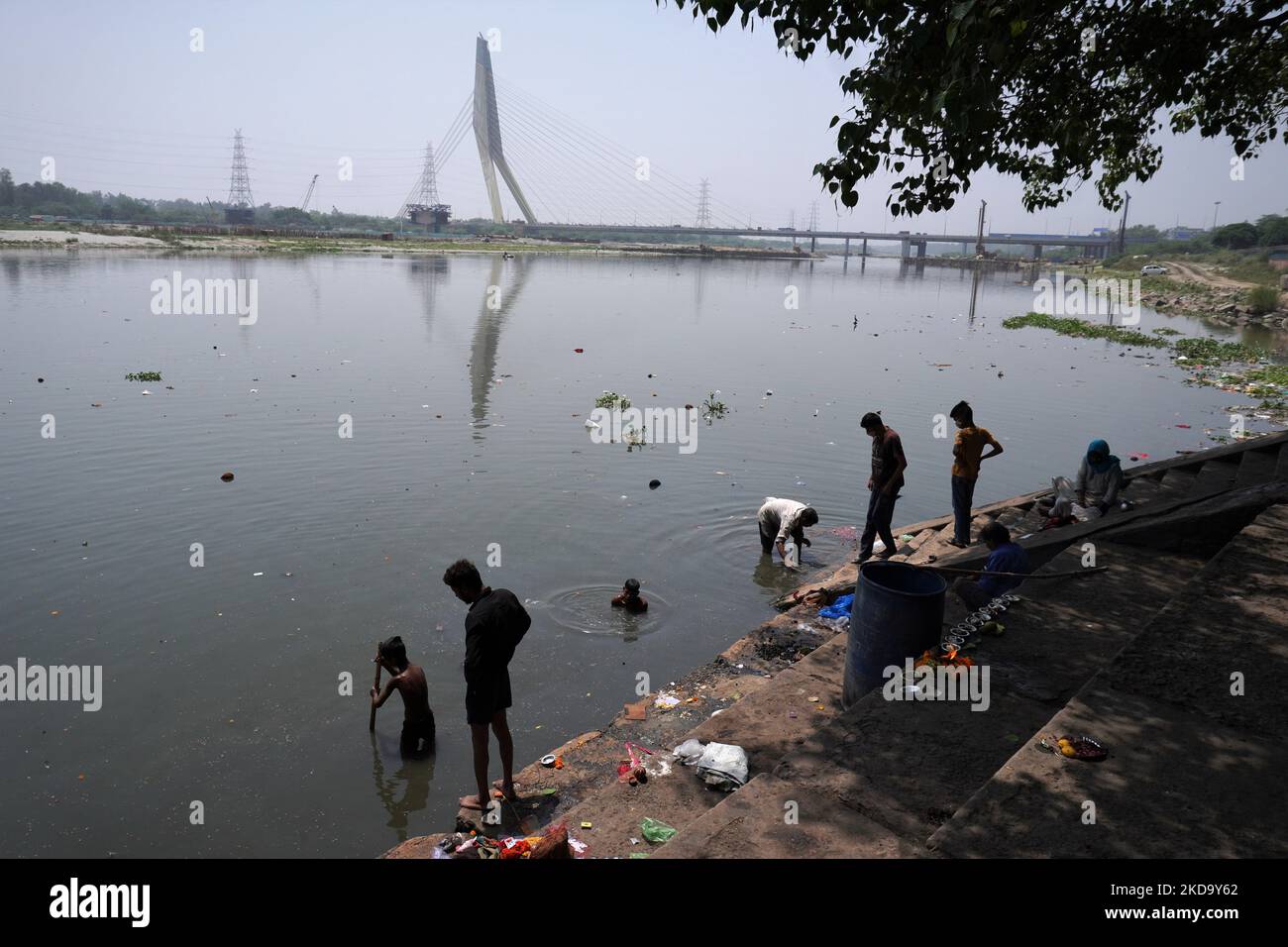 Gli uomini cercano materiali riciclabili nelle acque inquinate del fiume Yamuna, in una calda giornata estiva a Nuova Delhi, India, il 14 maggio 2022. Il 15 maggio di ogni anno si celebra la "Giornata mondiale del cambiamento climatico", per richiamare l'attenzione su un'ampia gamma di questioni ambientali, in particolare sul cambiamento climatico globale. (Foto di Mayank Makhija/NurPhoto) Foto Stock