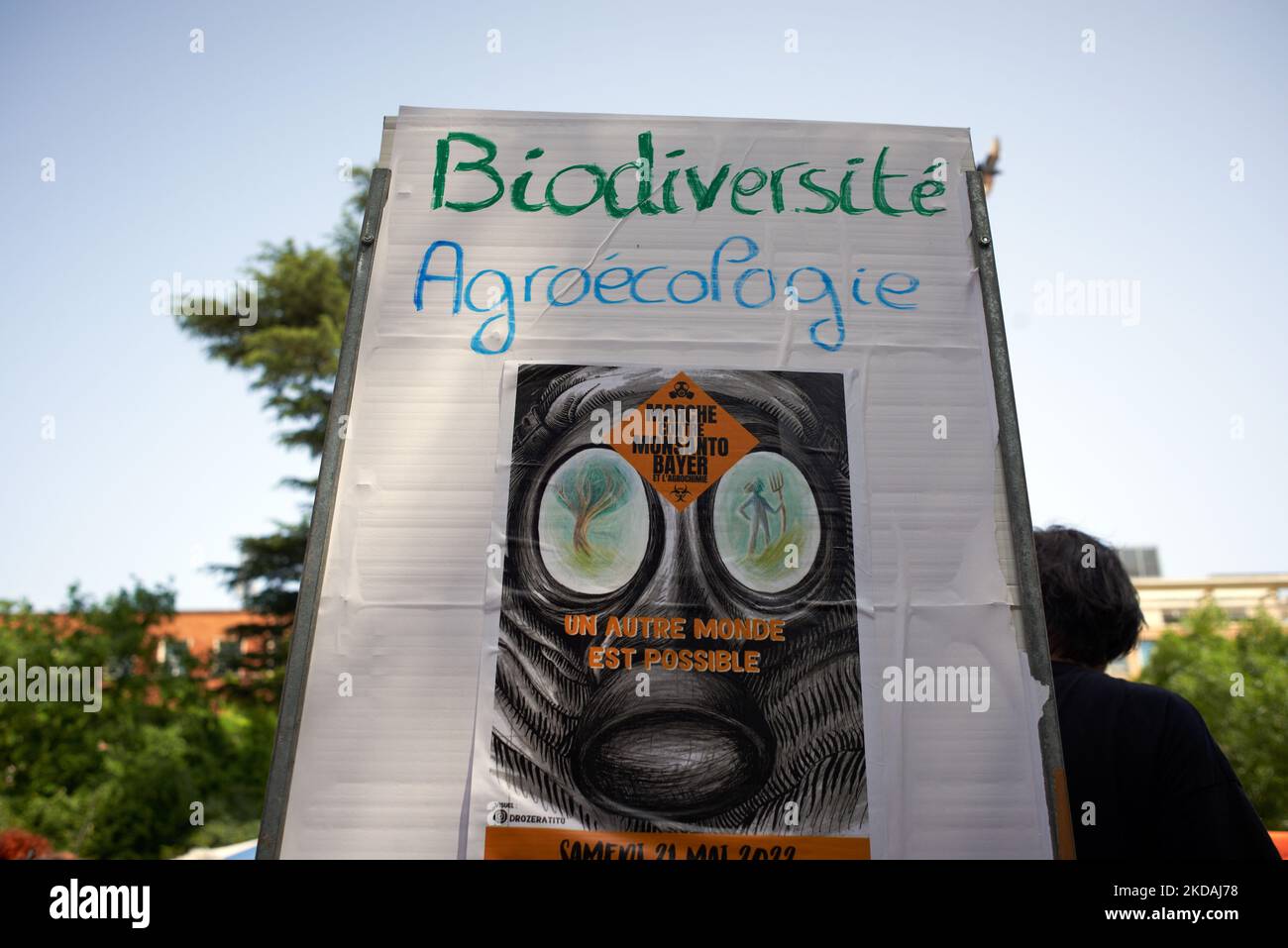 La targhetta recita "biodiversità, agroecologia un altro mondo è possibile”. Diverse ONG, associazioni (Faucheurs volontaires, XR, ecc.) hanno organizzato un incontro e una marcia contro Monsanto-Bayer come produttore di biocidi e OGM. Dicono che "fondono il mondo tossico di Monsanto-Bayer" come scandali e procedure di giustizia contro i biocidi'makers diventano più frequenti (Chlordecone, glifosato, agente arancione..). Difendono un'agricoltura biologica, la biodiversità, l'agroecologia e un cibo pulito e per tutti; per loro, la giustizia sociale ed ecologica va con un mondo migliore. Proteste simili si sono svolte altrove a fra Foto Stock