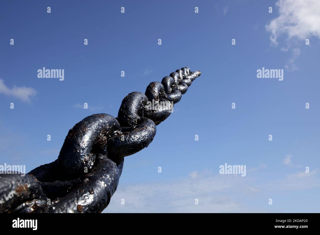 Una catena di ancoraggio in metallo pesante che va fino al cielo blu Foto Stock