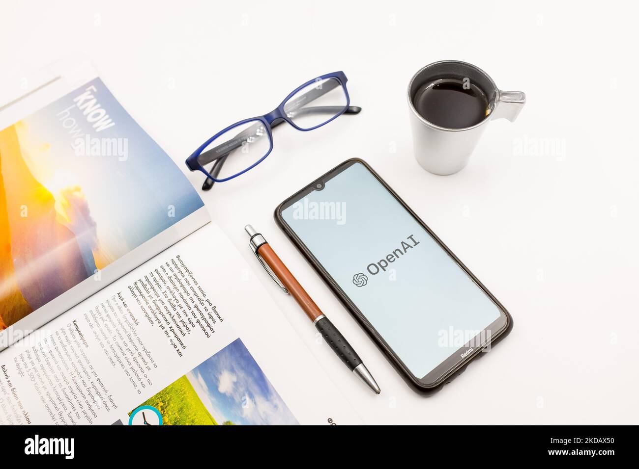 In questa foto, il 25 maggio 2022, un logo OpenAI visualizzato sullo schermo di uno smartphone su una scrivania accanto a un bar, una penna, occhiali e una rivista ad Atene, in Grecia. (Foto di Nikolas Kokovlis/NurPhoto) Foto Stock