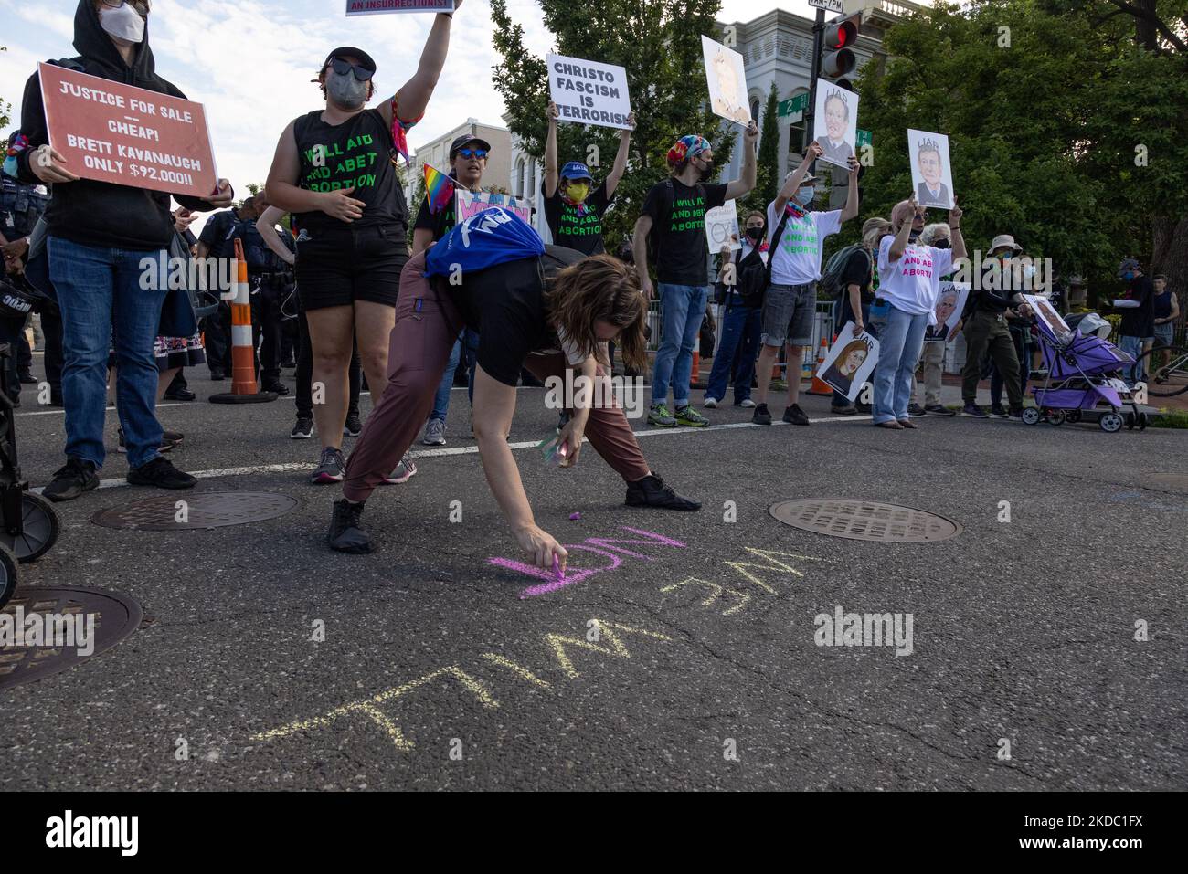 Un dimostratore scrive sul marciapiede con il gesso durante una marcia che tenta di circondare la Corte Suprema e bloccare le entrate veicolari a Washington, D.C. il 13 giugno 2022. (Foto di Bryan Olin Dozier/NurPhoto) Foto Stock