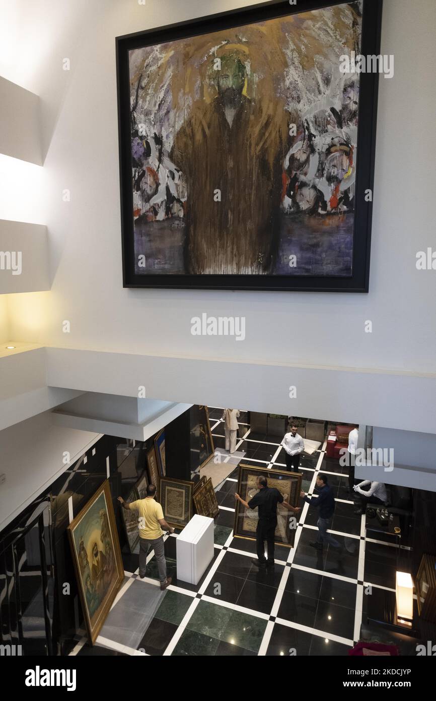 Un dipendente che porta con sé una calligrafia incorniciata da un calligrafo iraniano, Fardin Valizadeh, durante l'asta del mondo islamico e iraniano del 7th, tenuta dalla Casa d'aste Melli (Nazionale) in un centro conferenze a Teheran settentrionale il 24 giugno 2022. (Foto di Morteza Nikoubazl/NurPhoto) Foto Stock