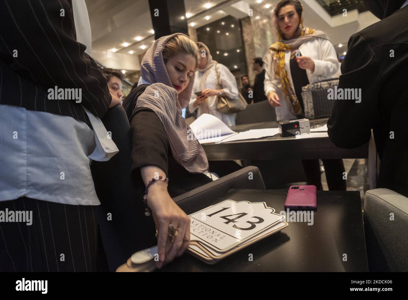 Una donna riceve un'asta mentre una donna si registra durante l'asta del mondo islamico e iraniano del 7th, tenuta dalla Melli (National) Auction House in un centro conferenze nel nord di Teheran il 24 giugno 2022. (Foto di Morteza Nikoubazl/NurPhoto) Foto Stock