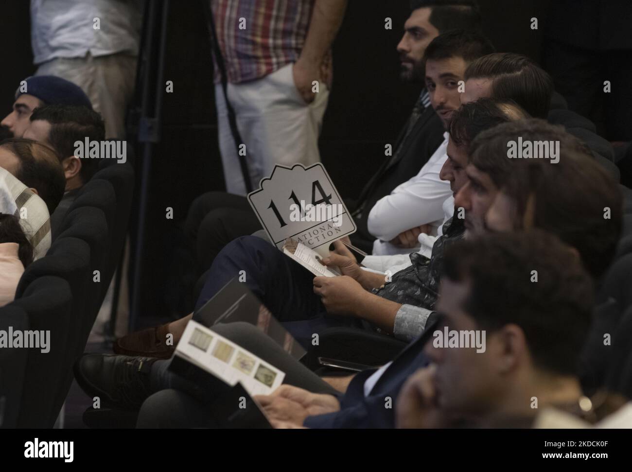 Un uomo iraniano tiene il suo segno d'offerta mentre siede in una sala d'asta durante l'asta del 7th Art of the Islamic and Iranian Worlds Auction, tenuta dalla Melli (National) Auction House in un centro conferenze nel nord di Teheran il 24 giugno 2022. (Foto di Morteza Nikoubazl/NurPhoto) Foto Stock