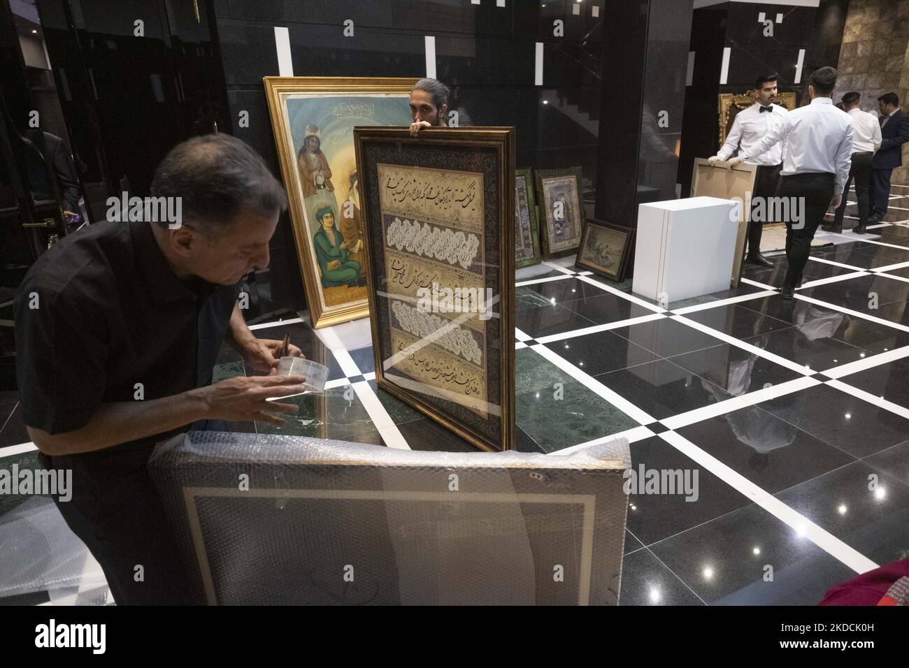 Un dipendente tiene una calligrafia incorniciata dal calligrafo iraniano Fardin Valizadeh, durante l'asta del mondo islamico e iraniano del 7th, tenuta dalla Casa d'aste Melli (Nazionale) in un centro conferenze a Teheran settentrionale il 24 giugno 2022. (Foto di Morteza Nikoubazl/NurPhoto) Foto Stock