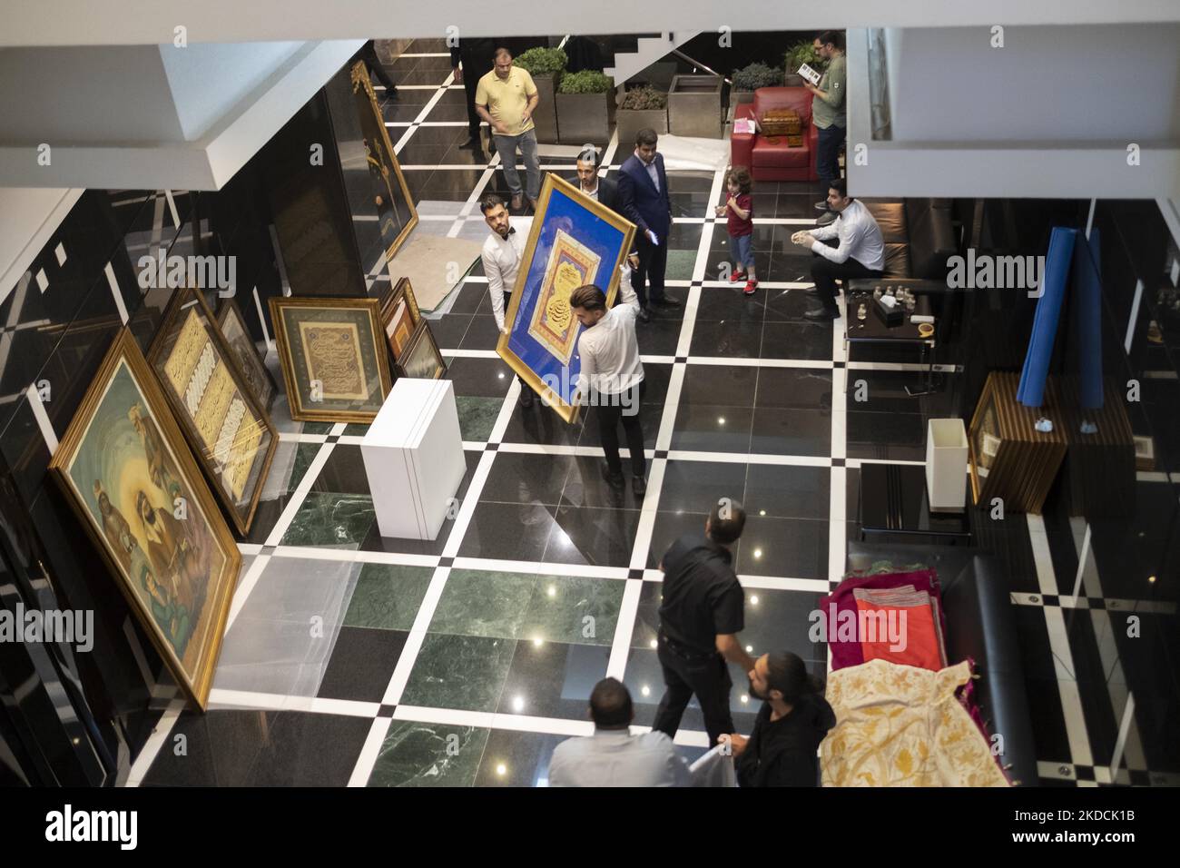 Due dipendenti che riportavano una calligrafia incorniciata al backstage durante l'asta del mondo islamico e iraniano del 7th, tenuta dalla Melli (National) Auction House in un centro conferenze nel nord di Teheran il 24 giugno 2022. (Foto di Morteza Nikoubazl/NurPhoto) Foto Stock