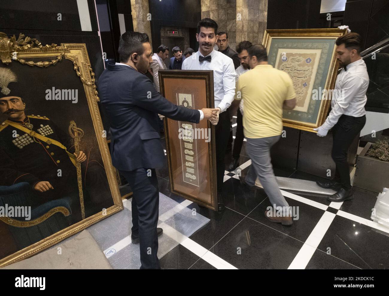 Un dipendente che riporta una calligrafia incorniciata al backstage durante l'asta del mondo islamico e iraniano del 7th, tenuta dalla Melli (National) Auction House in un centro conferenze nel nord di Teheran il 24 giugno 2022. (Foto di Morteza Nikoubazl/NurPhoto) Foto Stock