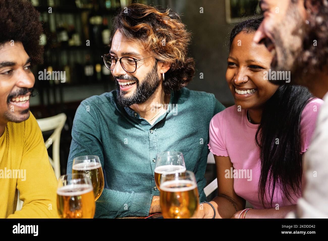 Felici colleghi di lavoro multirazziali sorseggiando un drink dopo il lavoro al bar della birreria Foto Stock