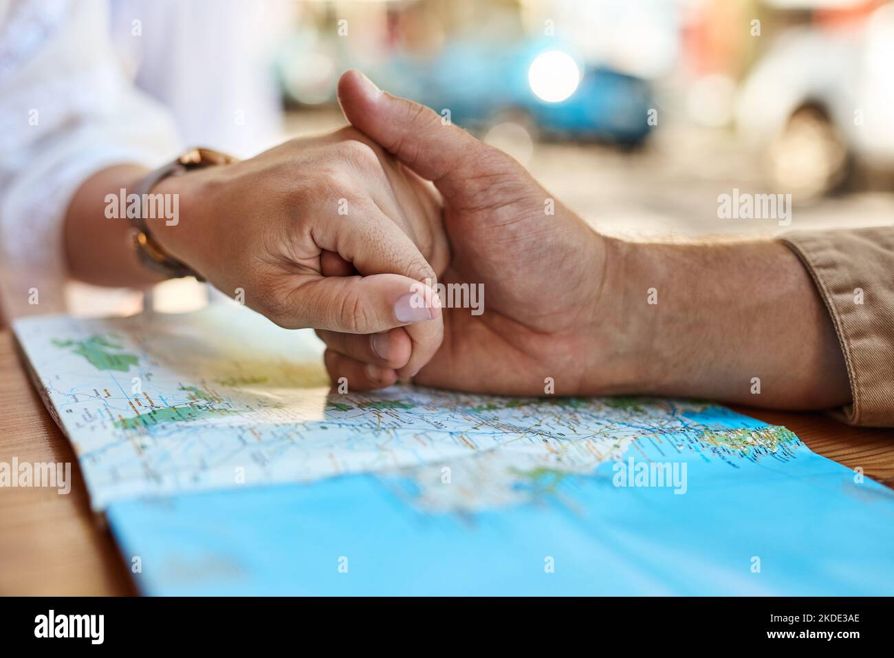 Mano in mano intorno al mondo. Una coppia turistica non identificabile che tiene le mani mentre guarda una mappa in un caffè marciapiede. Foto Stock