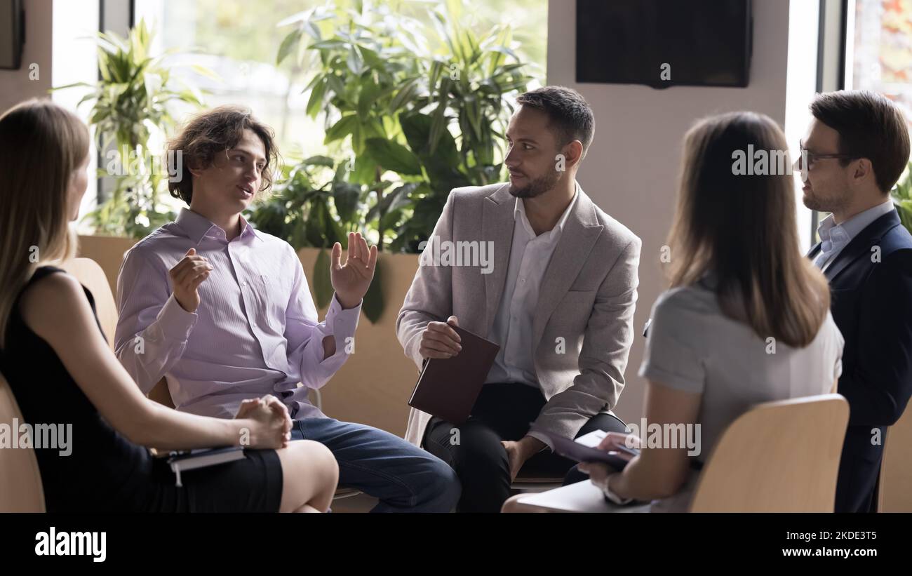 Cinque dipendenti prendono parte a briefing di gruppo riuniti in ufficio Foto Stock