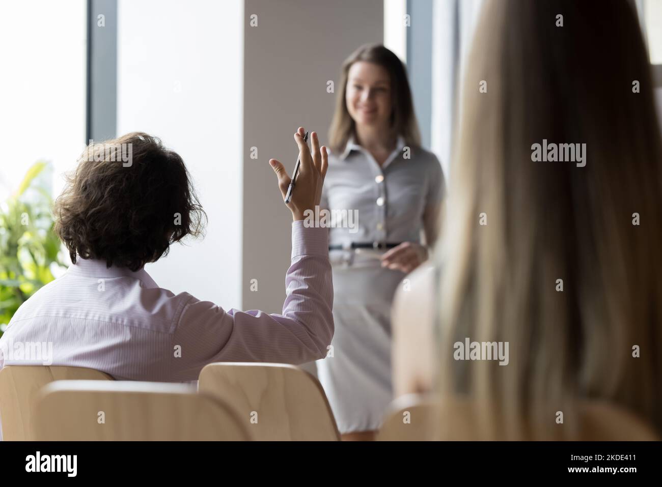 La vista posteriore del partecipante al seminario educativo solleva il braccio che ha domande Foto Stock
