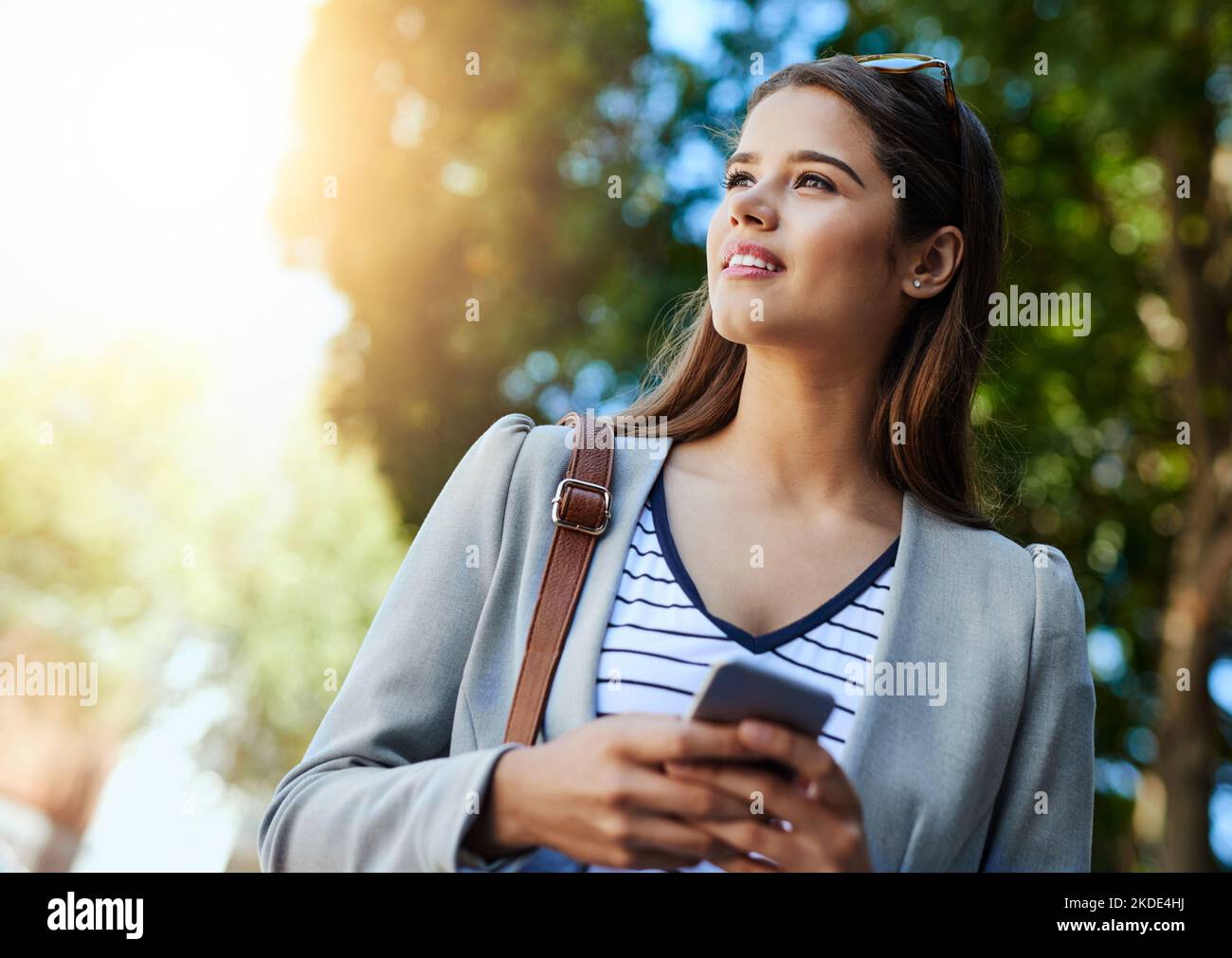 Far sapere ai suoi colleghi che è in viaggio: Una giovane donna attraente che usa il suo cellulare mentre si trova in viaggio per lavoro. Foto Stock