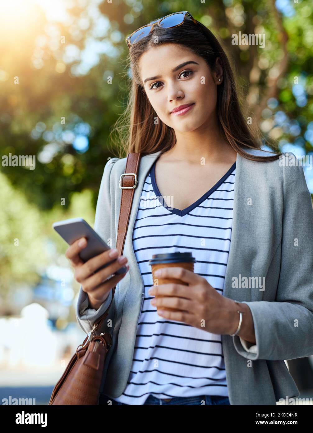 La comunicazione è fondamentale per il business. Ritratto ritagliato di una giovane donna attraente utilizzando il suo cellulare mentre si è in viaggio per lavoro. Foto Stock