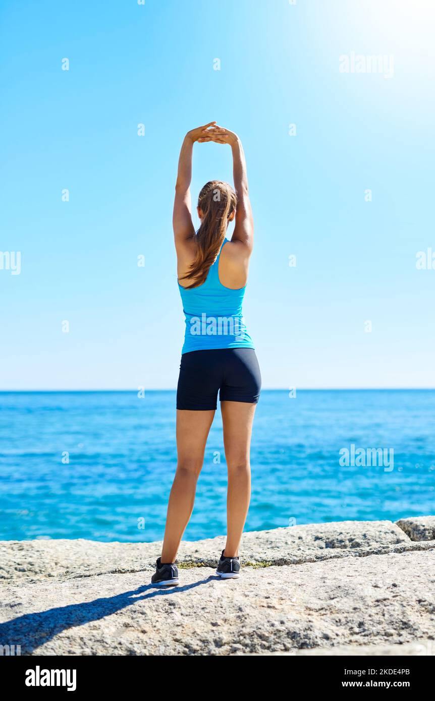 Assicuratevi che lo stretching faccia parte del vostro allenamento. Una giovane donna che si stretching prima della sua corsa. Foto Stock