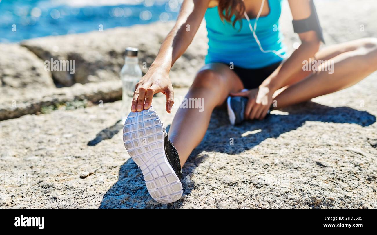 Stretching è un'abitudine sana che realmente paga fuori. Una giovane donna che si allunga prima della sua corsa. Foto Stock