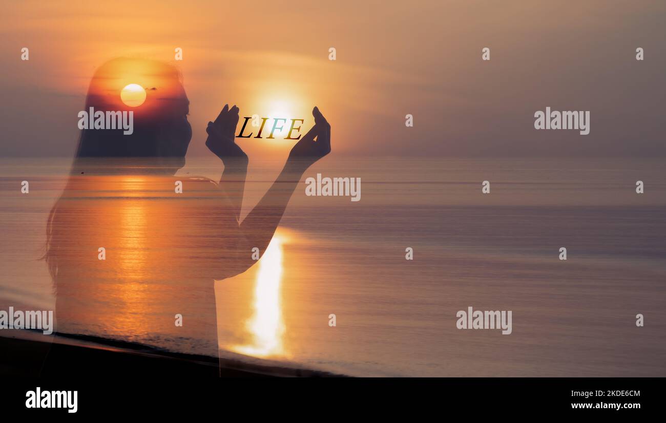 Human Healthy Life Balance Concept, Donna che tiene il sole in mano con il testo DEL personaggio DELLA VITA all'alba sulla spiaggia. Foto Stock