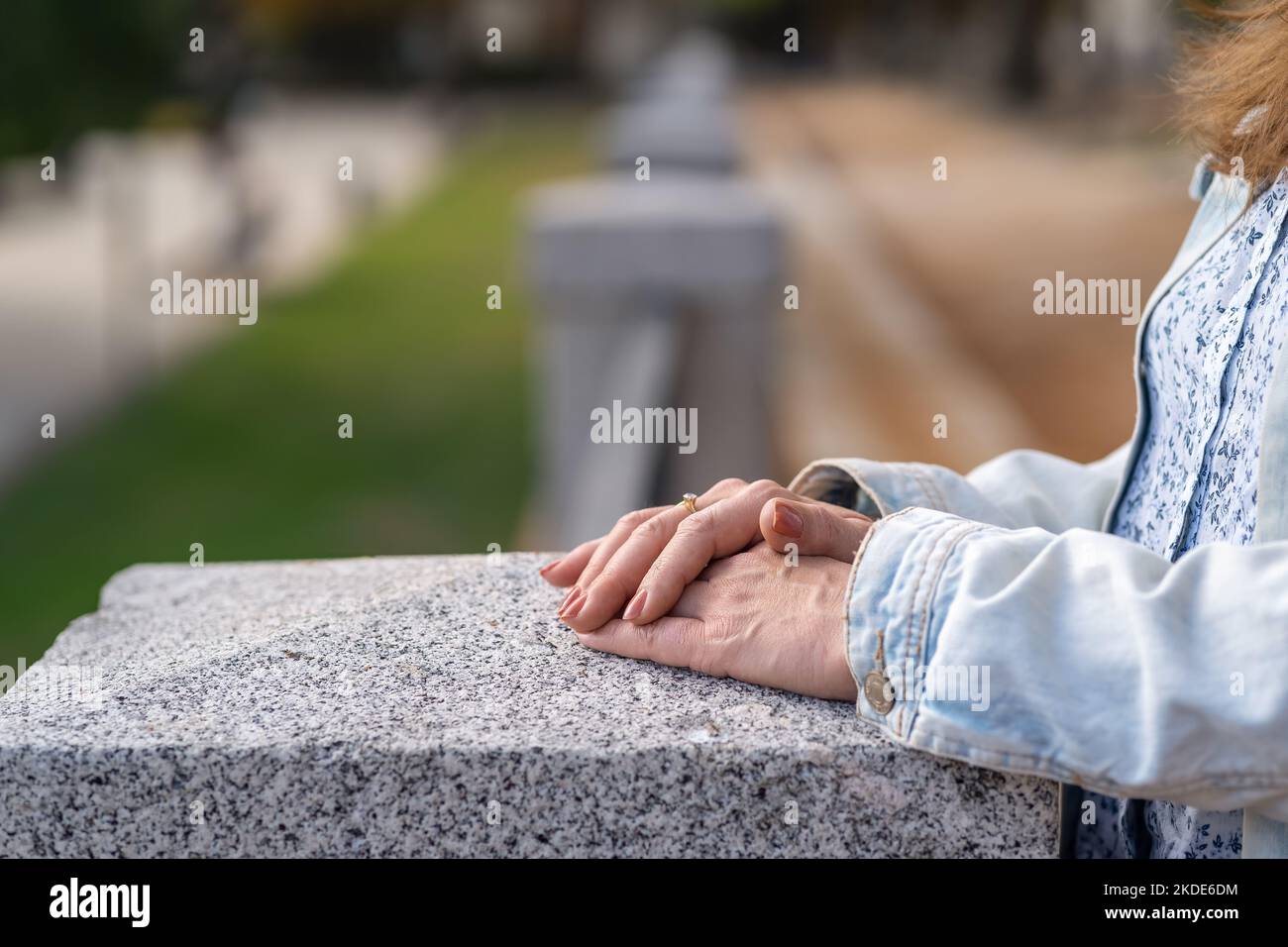 Le mani delle donne appoggiate su una colonna di pietra in un parco pubblico in un atteggiamento rilassato, foto copyspace. Foto Stock