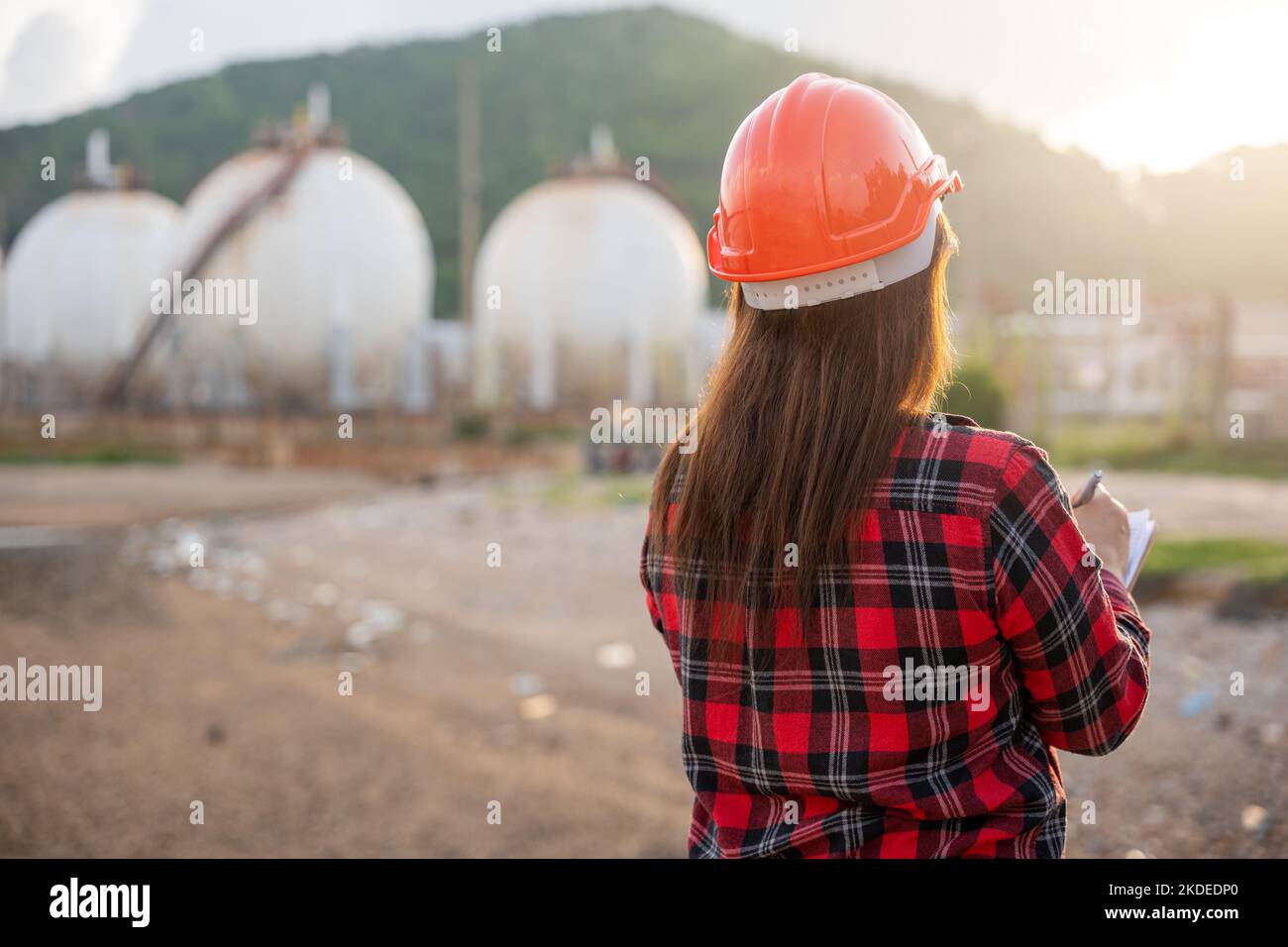 Donna operatrice asiatica felice nell'industria chimica del petrolio che lavora elenco di ispezione visiva sulla clipboard in pianta Foto Stock