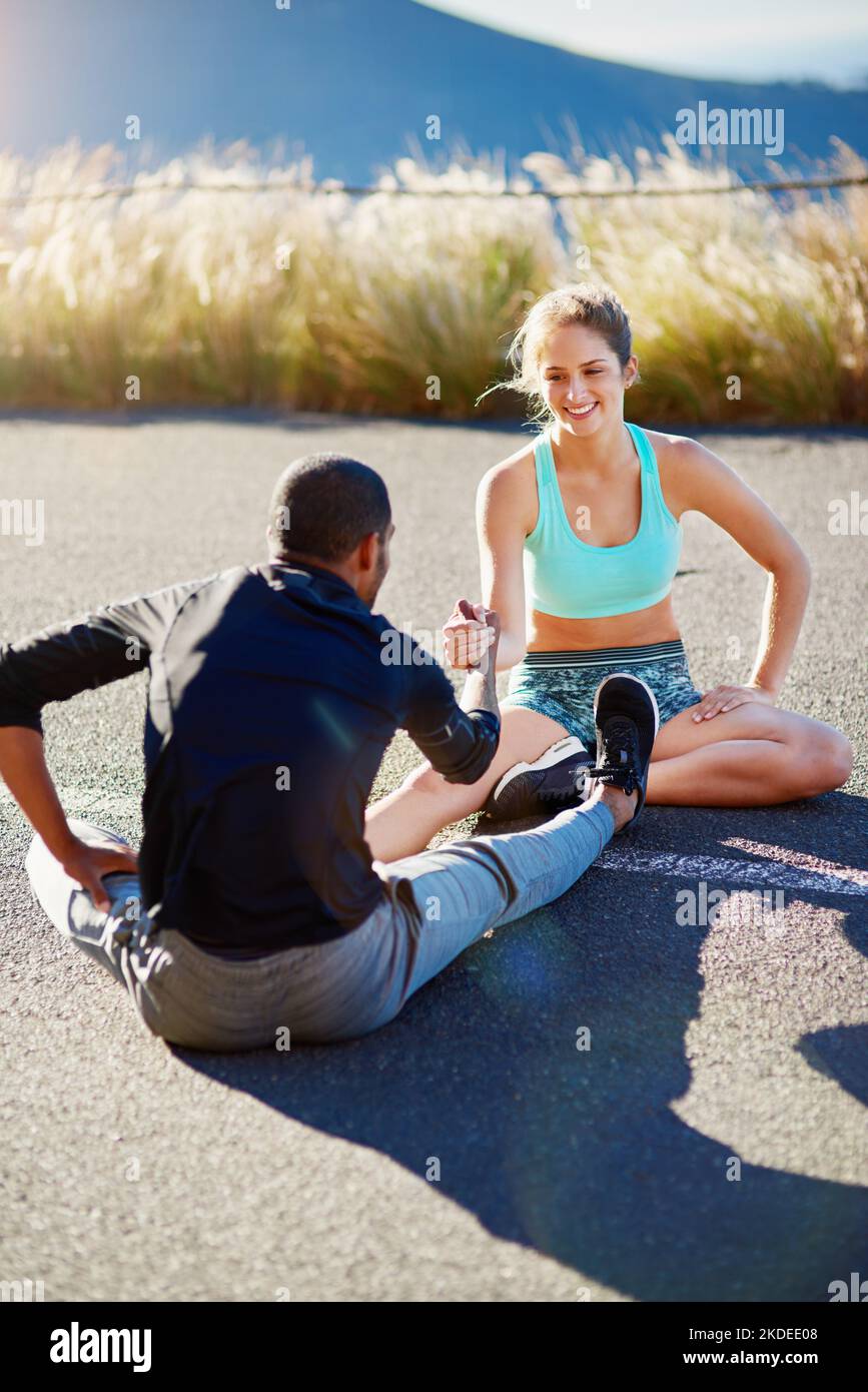 Potremmo fare tutti con una certa motivazione: Una giovane coppia sportiva che si allunga prima di una corsa all'aperto. Foto Stock