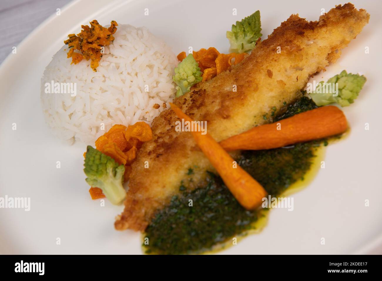 Ricetta per filetto di nasello impanato con panko, riso, patatine di carote e salsa di coriandolo Foto Stock