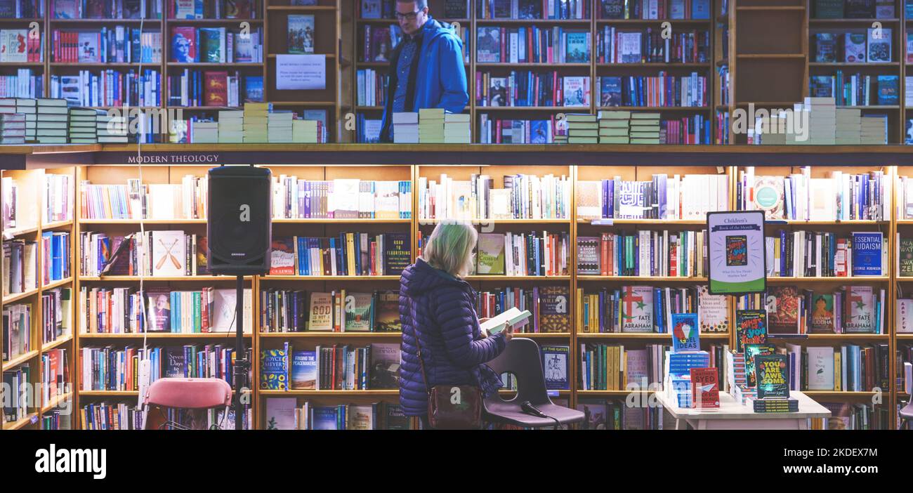 Due persone che sfogliano libri nella libreria di Oxfords Blackwell, una al piano superiore, una al piano inferiore. Foto Stock