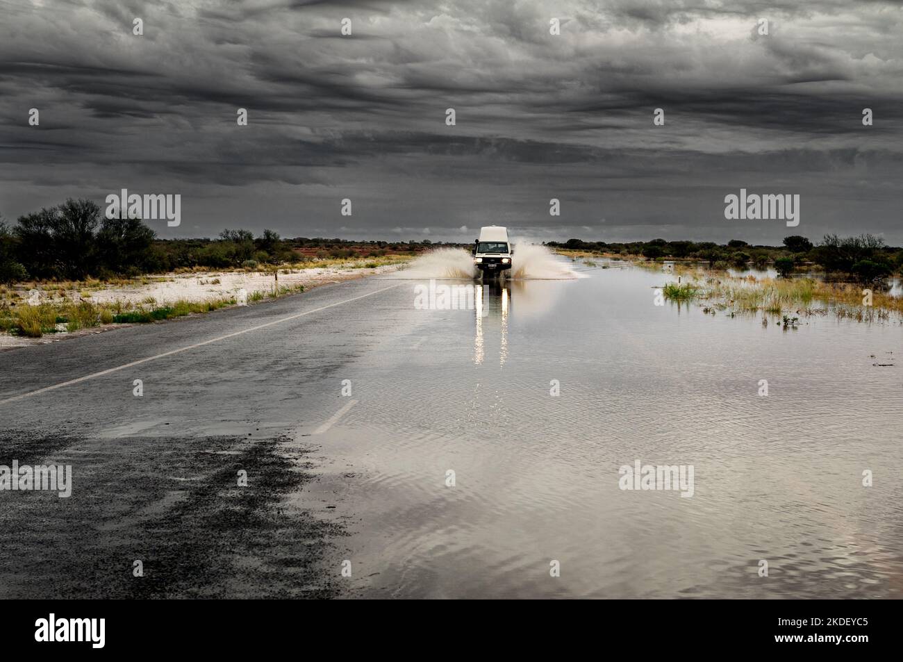 Auto che guida su una strada allagata nell'Outback australiano. Foto Stock