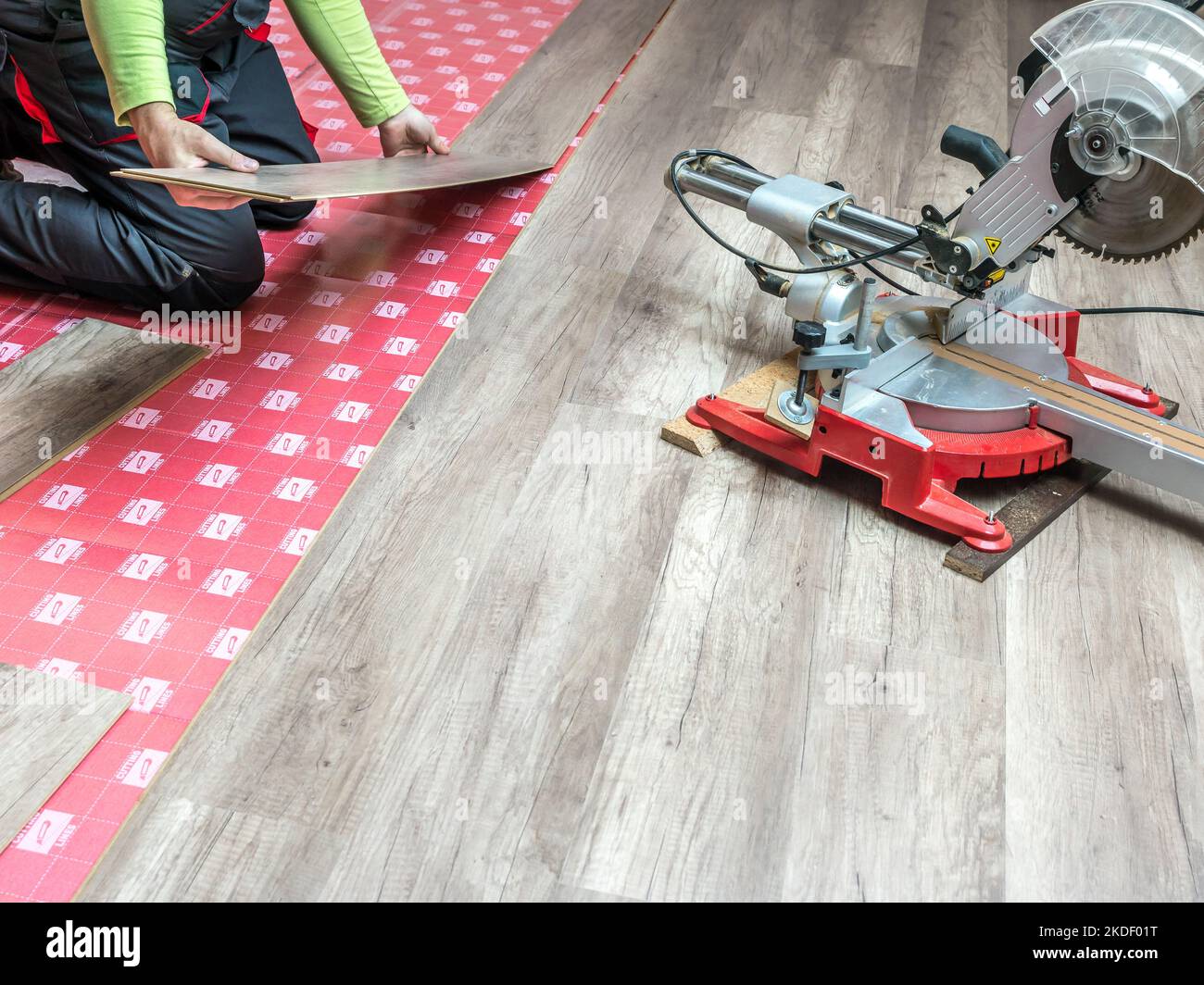 Un falegname posa nuovo pannello laminato pavimento in casa appartamento Foto Stock