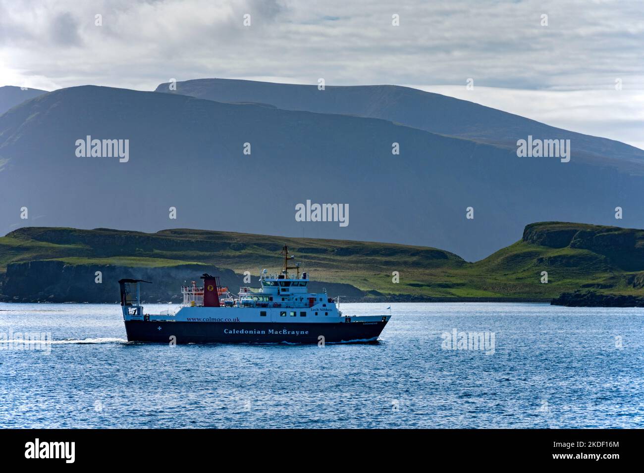 Il traghetto delle piccole isole MacBrayne della Caledonia, il MV Lochnevis, che entra nel porto, Isola di canna, Scozia, REGNO UNITO. Le montagne di Rum dietro. Foto Stock