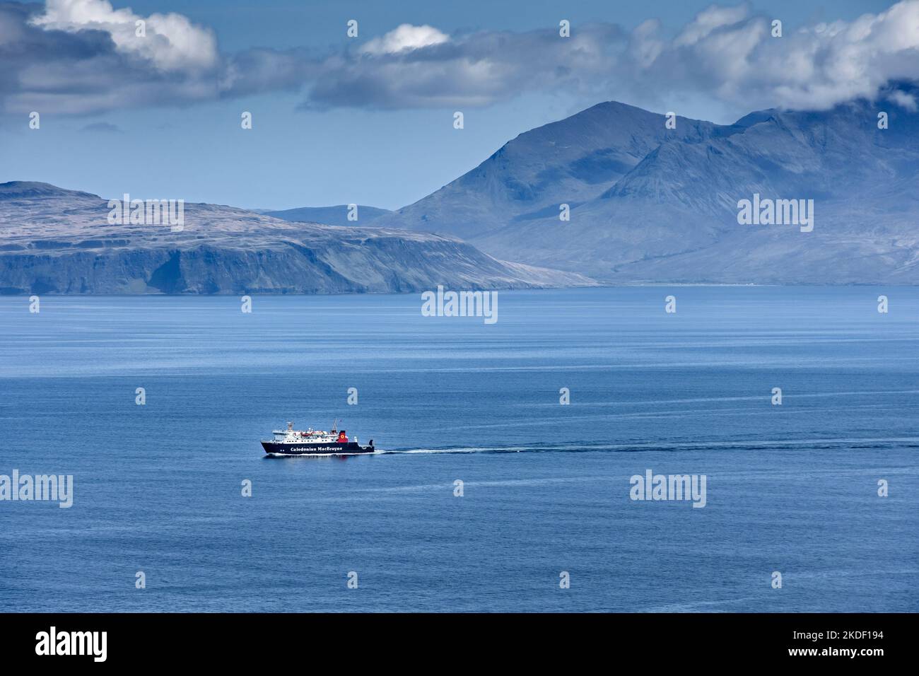 Il traghetto delle piccole isole MacBrayne Caledonian, il MV Lochnevis, lascia l'isola di canna, Scozia, Regno Unito. Le colline di Rum dietro. Foto Stock