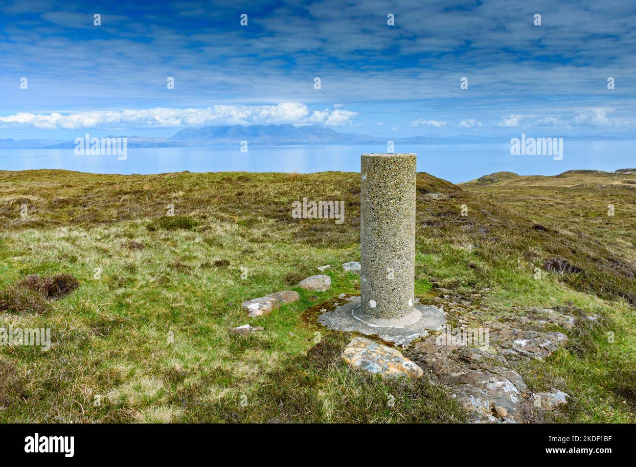 Il punto di trig alla cima di Carn A' Ghaill, il punto più alto dell'isola di canna, Scozia, Regno Unito. Le montagne Cuillin di Skye in lontananza. Foto Stock