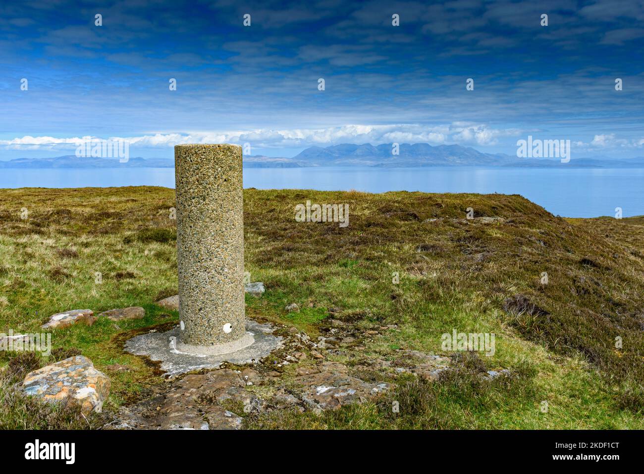 Il punto di trig alla cima di Carn A' Ghaill, il punto più alto dell'isola di canna, Scozia, Regno Unito. Le montagne Cuillin di Skye in lontananza. Foto Stock