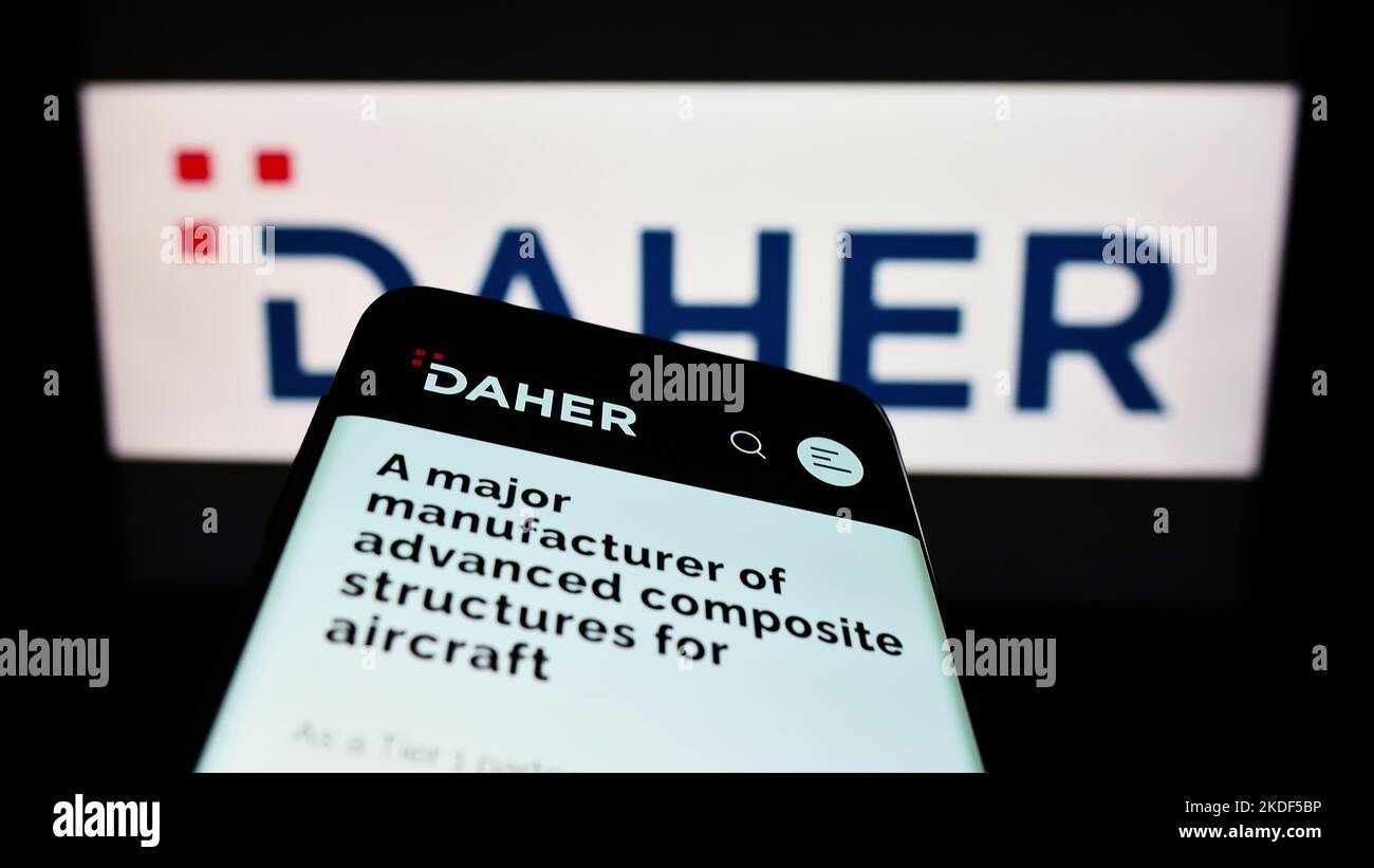 Smartphone con pagina web della società aerospaziale francese Daher Group sullo schermo di fronte al logo aziendale. Messa a fuoco in alto a sinistra del display del telefono. Foto Stock