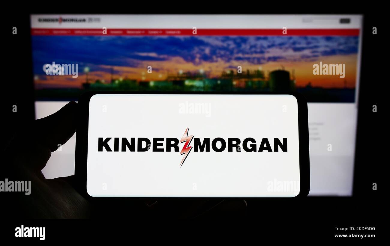 Persona che tiene in mano uno smartphone con il logo della società americana Kinder Morgan Inc. Sull'immagine davanti al sito Web. Messa a fuoco sul display del telefono. Foto Stock