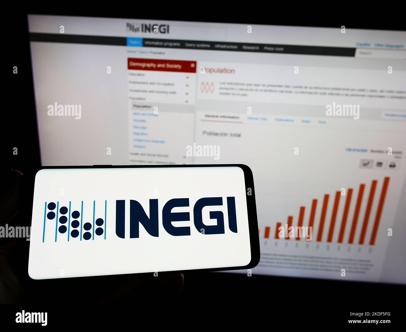 Persona in possesso di smartphone con il logo dell'agenzia di statistiche messicane INEGI sullo schermo di fronte al sito web. Messa a fuoco sul display del telefono. Foto Stock