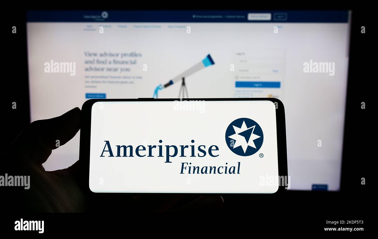 Persona che tiene il cellulare con il logo della società americana Ameriprise Financial Inc. Sullo schermo di fronte al sito web aziendale. Messa a fuoco sul display del telefono. Foto Stock