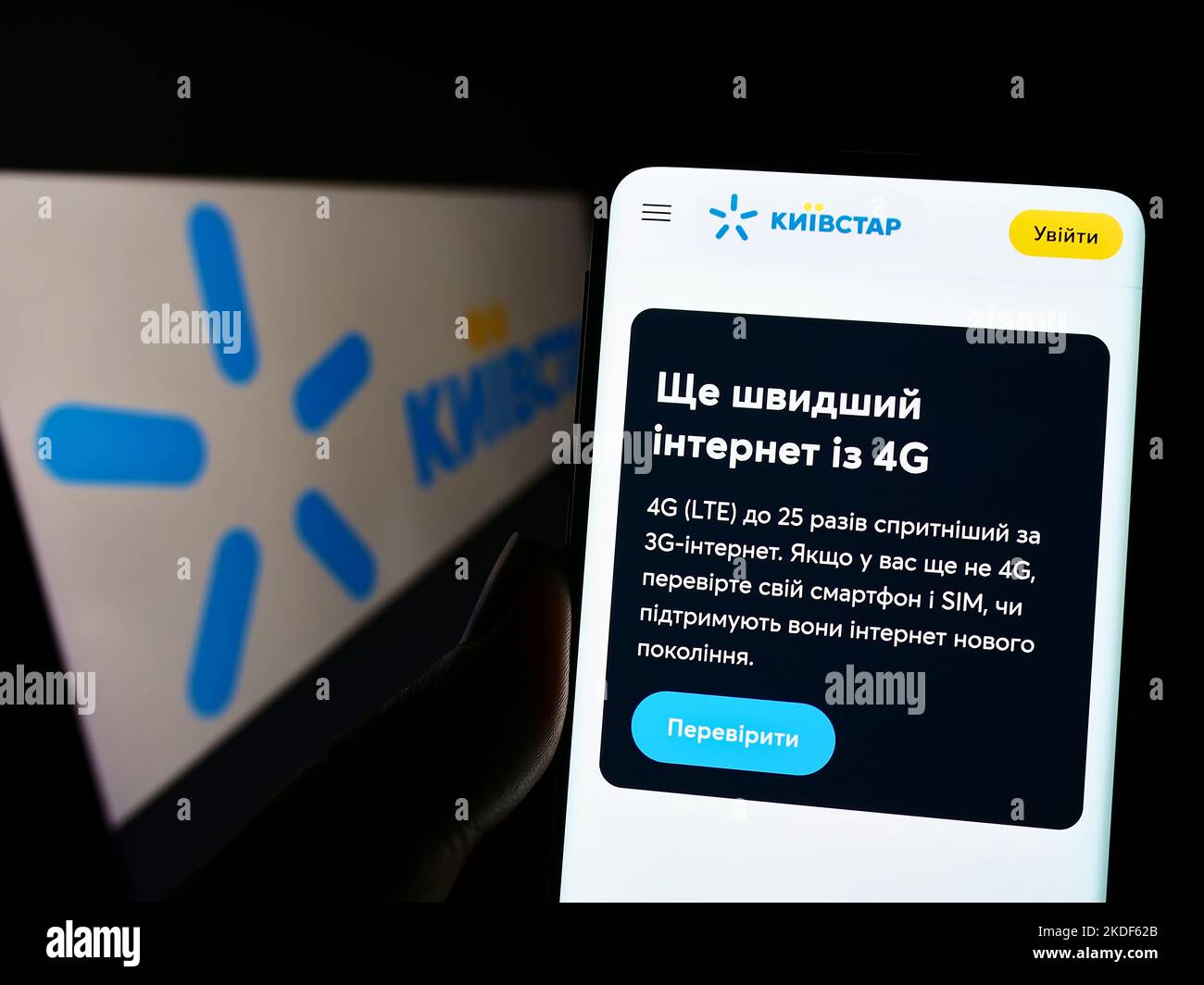 Persona in possesso di cellulare con pagina web della società di telecomunicazioni Kyivstar JSC sullo schermo di fronte al logo. Messa a fuoco al centro del display del telefono. Foto Stock
