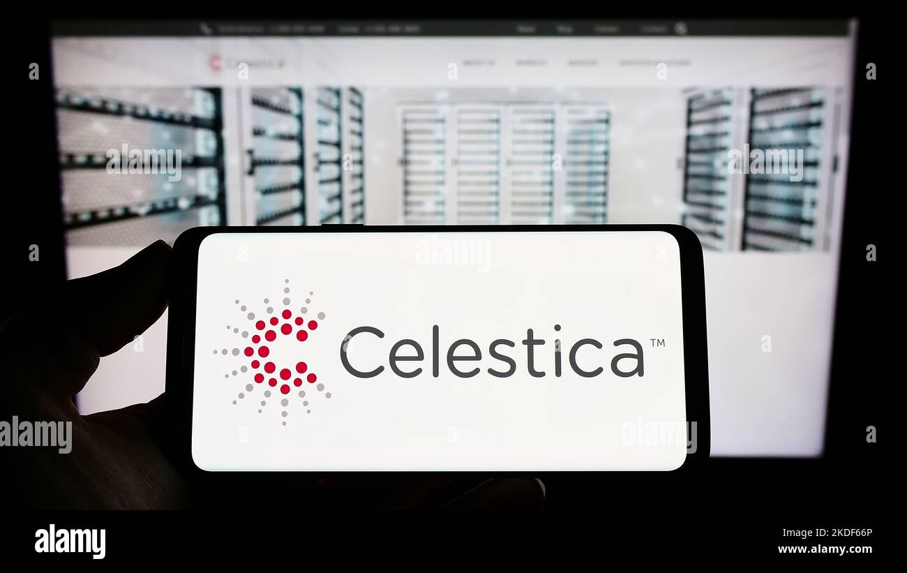 Persona che tiene il telefono cellulare con il logo della società di elettronica canadese Celestica Inc. Sullo schermo di fronte alla pagina web. Messa a fuoco sul display del telefono. Foto Stock