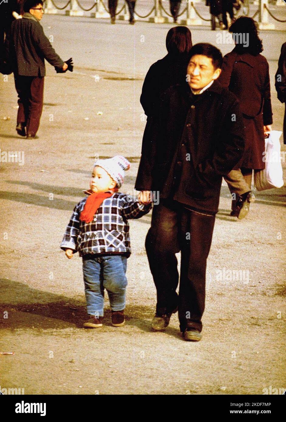 Padre e figlio, People's Square Shanghai, dicembre 1981. Il bambino indossa abiti dai colori vivaci, una comtrast con gli adulti Foto Stock