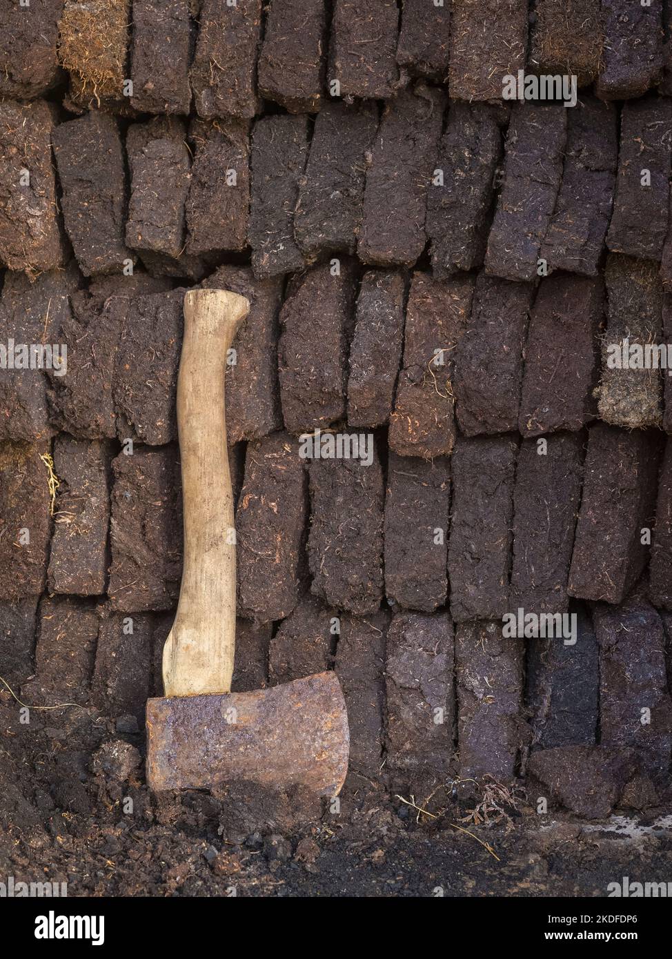 Blocchi di torba impilati in croft capannone con ascia per tagliare la torba, Shetland continentale, Shetland Foto Stock