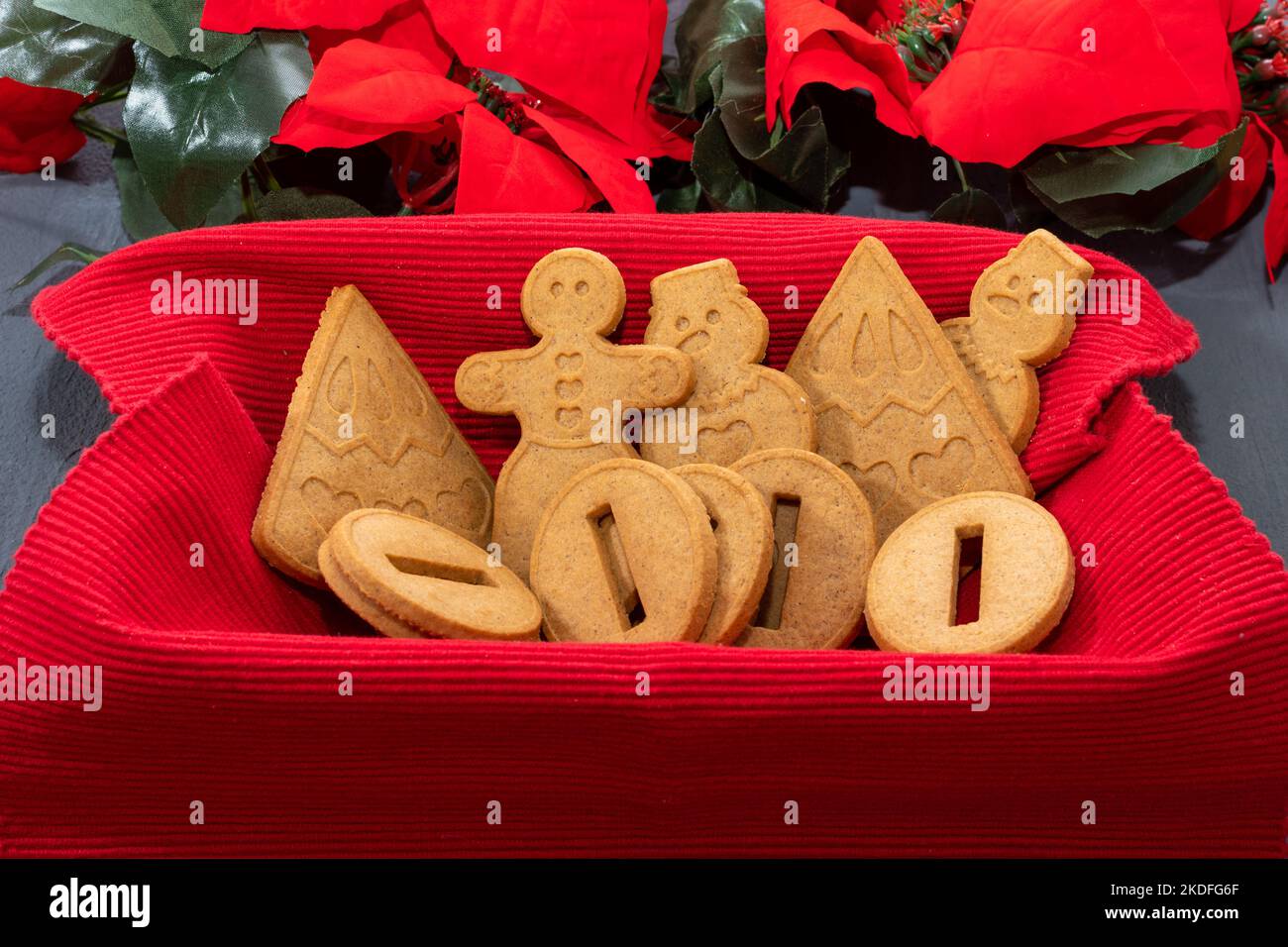 Delizioso pan di zenzero di Natale fatto in casa in un cestino su un tovagliolo rosso su uno sfondo verde, primo piano. Foto Stock