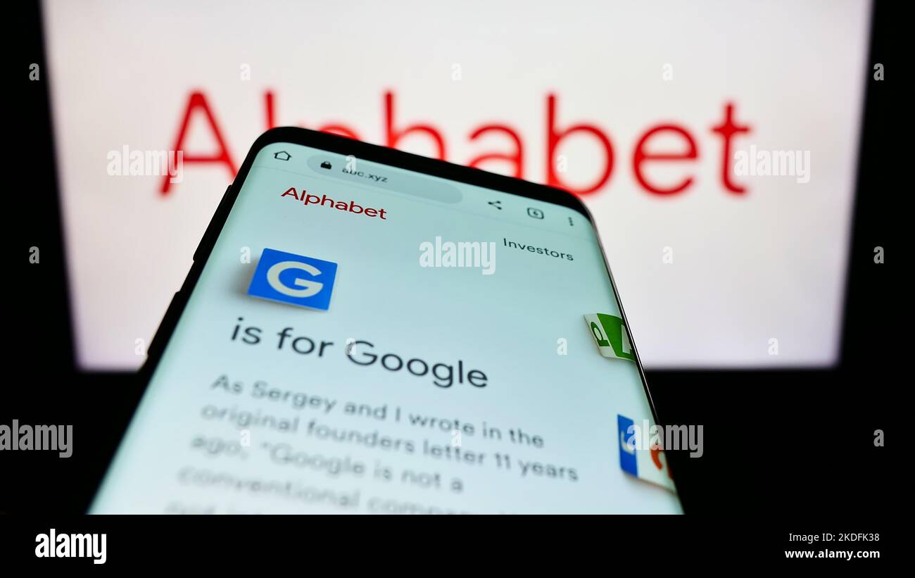 Smartphone con sito Web della holding statunitense Alphabet Inc. (Google) sullo schermo di fronte al logo aziendale. Messa a fuoco in alto a sinistra del display del telefono. Foto Stock