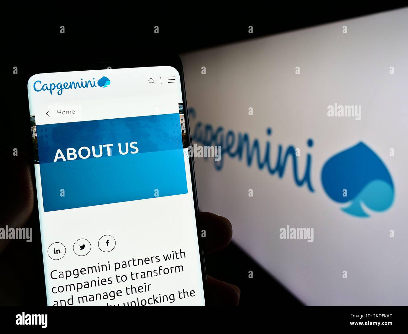 Persona che tiene uno smartphone con il sito web della società di tecnologia informatica Capgemini se sullo schermo di fronte al logo. Messa a fuoco al centro del display del telefono. Foto Stock