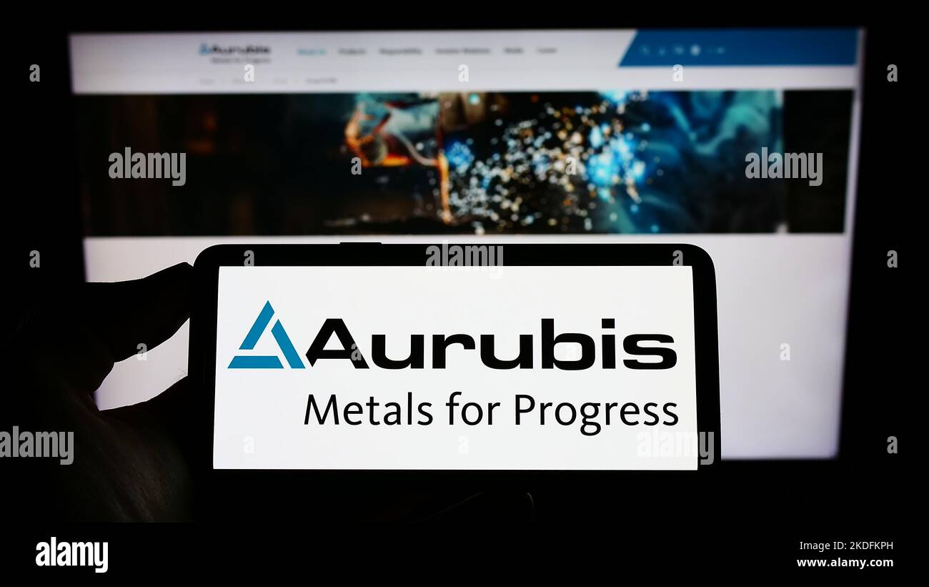 Persona in possesso di smartphone con il logo della società tedesca di rame Aurubis AG sullo schermo di fronte al sito Web. Messa a fuoco sul display del telefono. Foto Stock