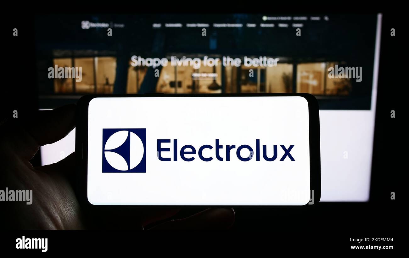 Persona che tiene in mano uno smartphone con il logo dell'azienda svedese Electrolux AB sullo schermo di fronte al sito Web. Messa a fuoco sul display del telefono. Foto Stock