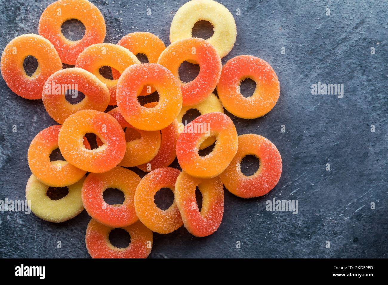 Vista dall'alto verso il basso di vivaci anelli gommoso al gusto di pesca ricoperti di zucchero. Foto Stock