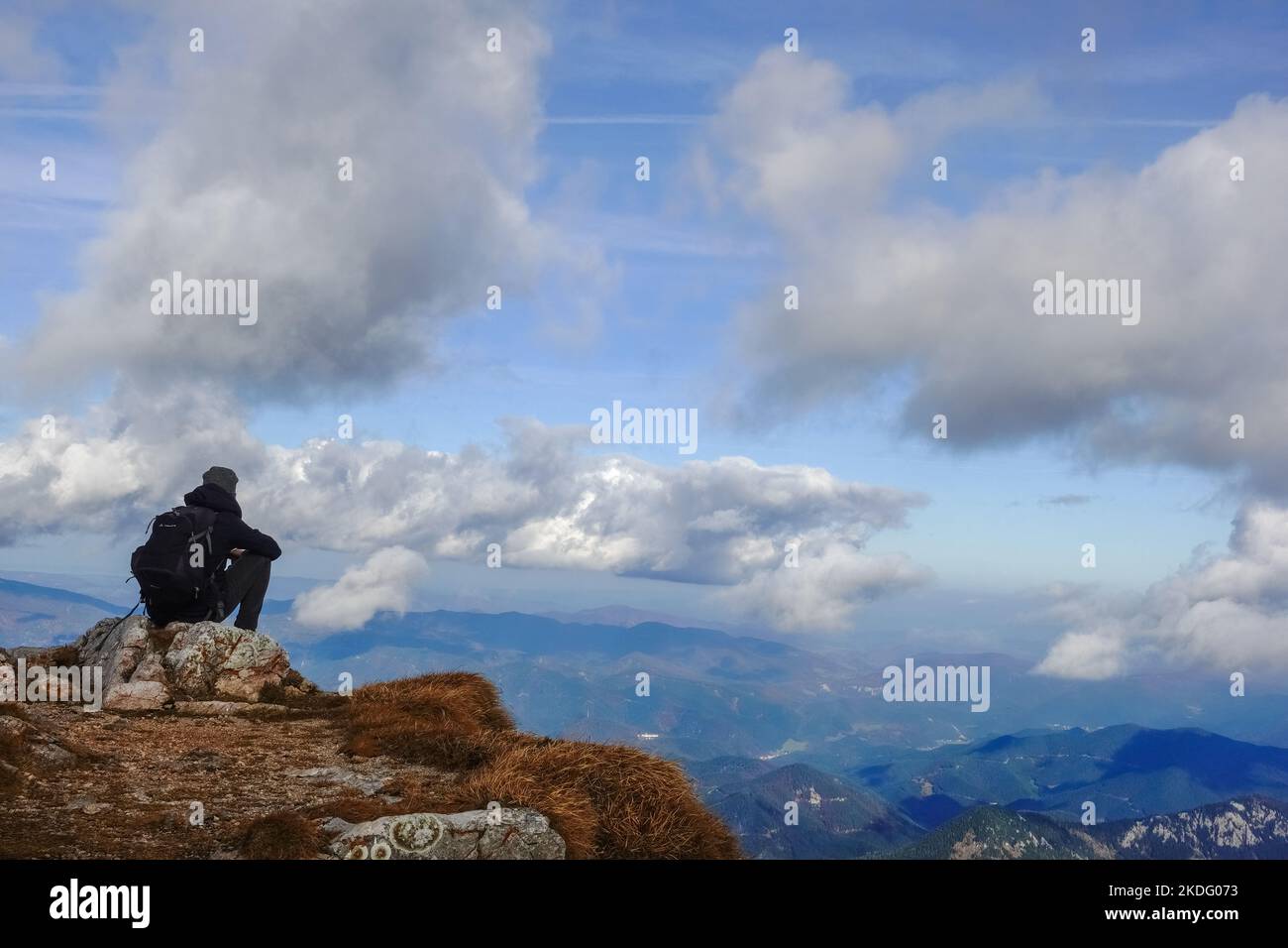 l'escursionista singolo si siede su una roccia e guarda al paesaggio di montagna con un cielo incredibile Foto Stock
