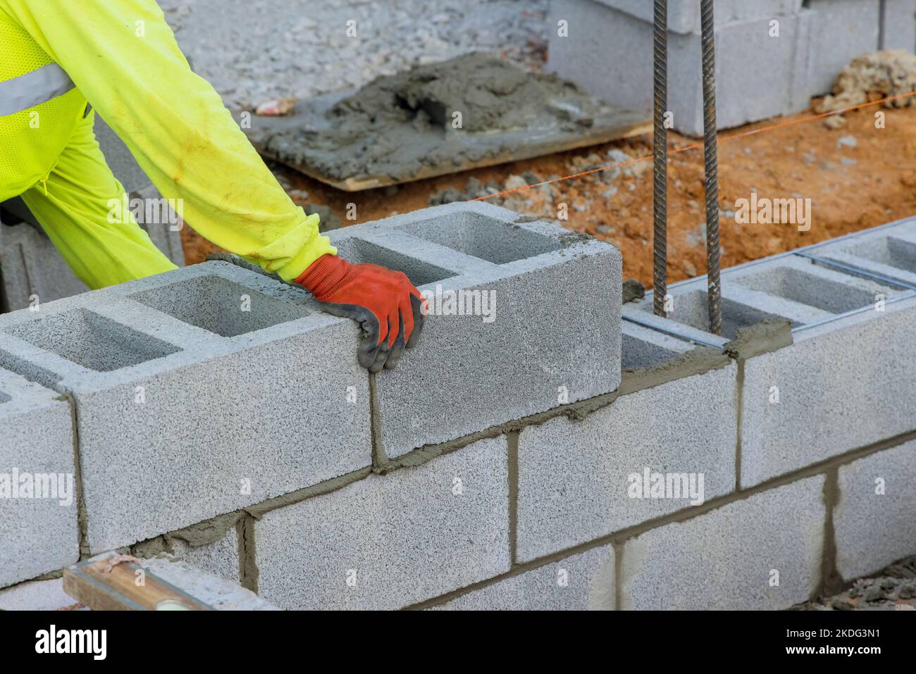 Muratore sta mettendo giù un'altra fila di blocchi di cemento come parte del processo di costruzione Foto Stock