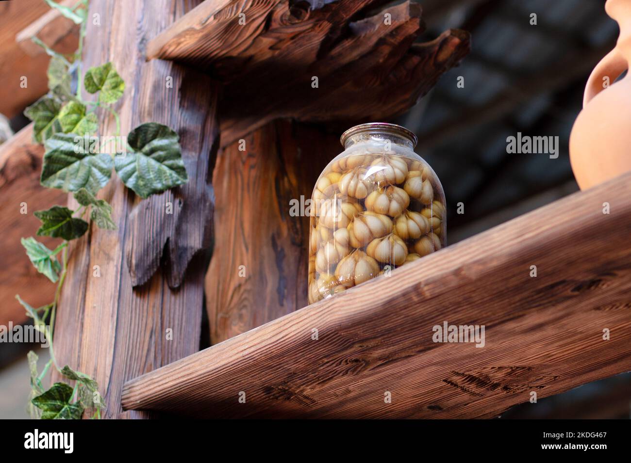 aglio sott'aceto in un grande vaso di vetro su una mensola di legno. Aglio saporito sottaceto Foto Stock