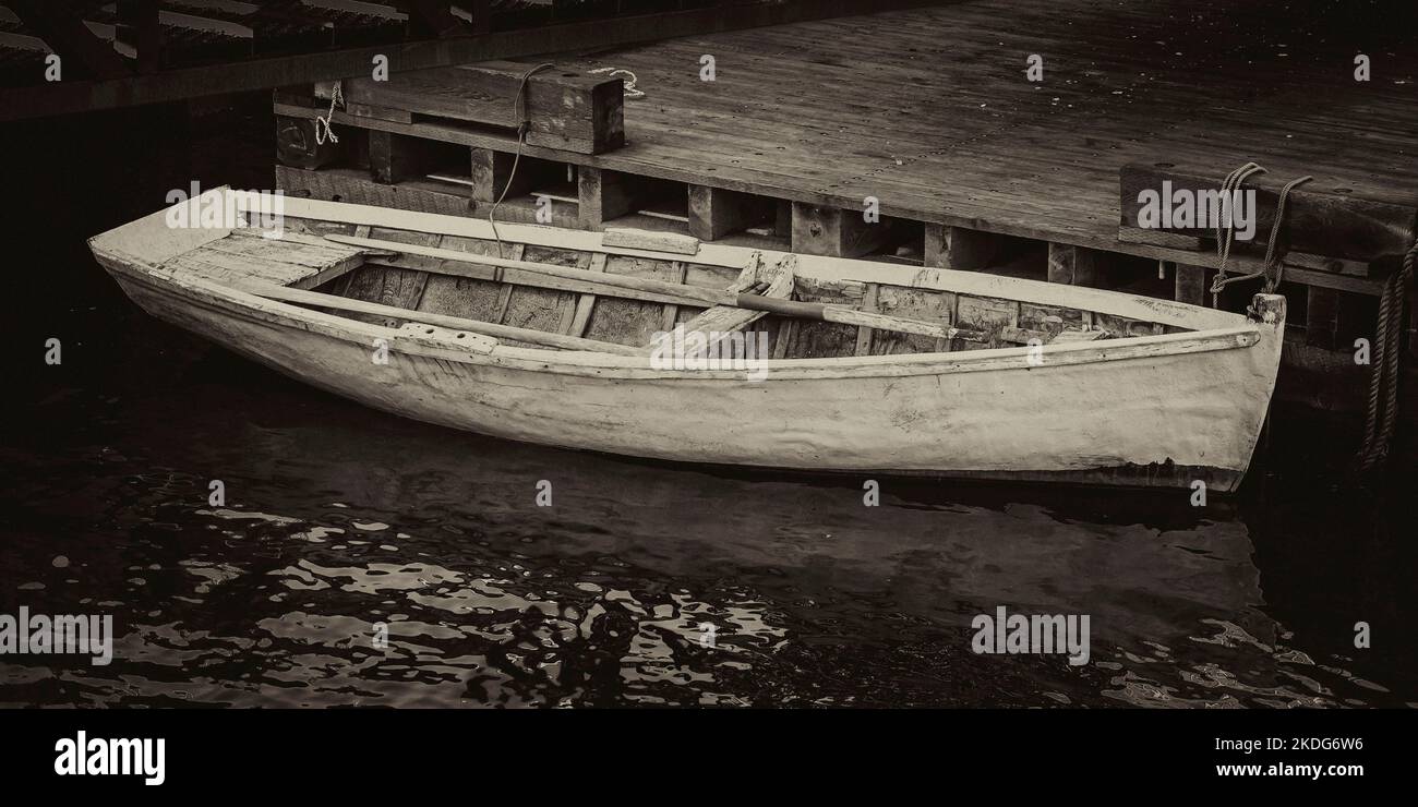 Una barca a remi (chaloupe) legata al porto di pesca di Lepreau, NB in tonalità seppia. Foto Stock