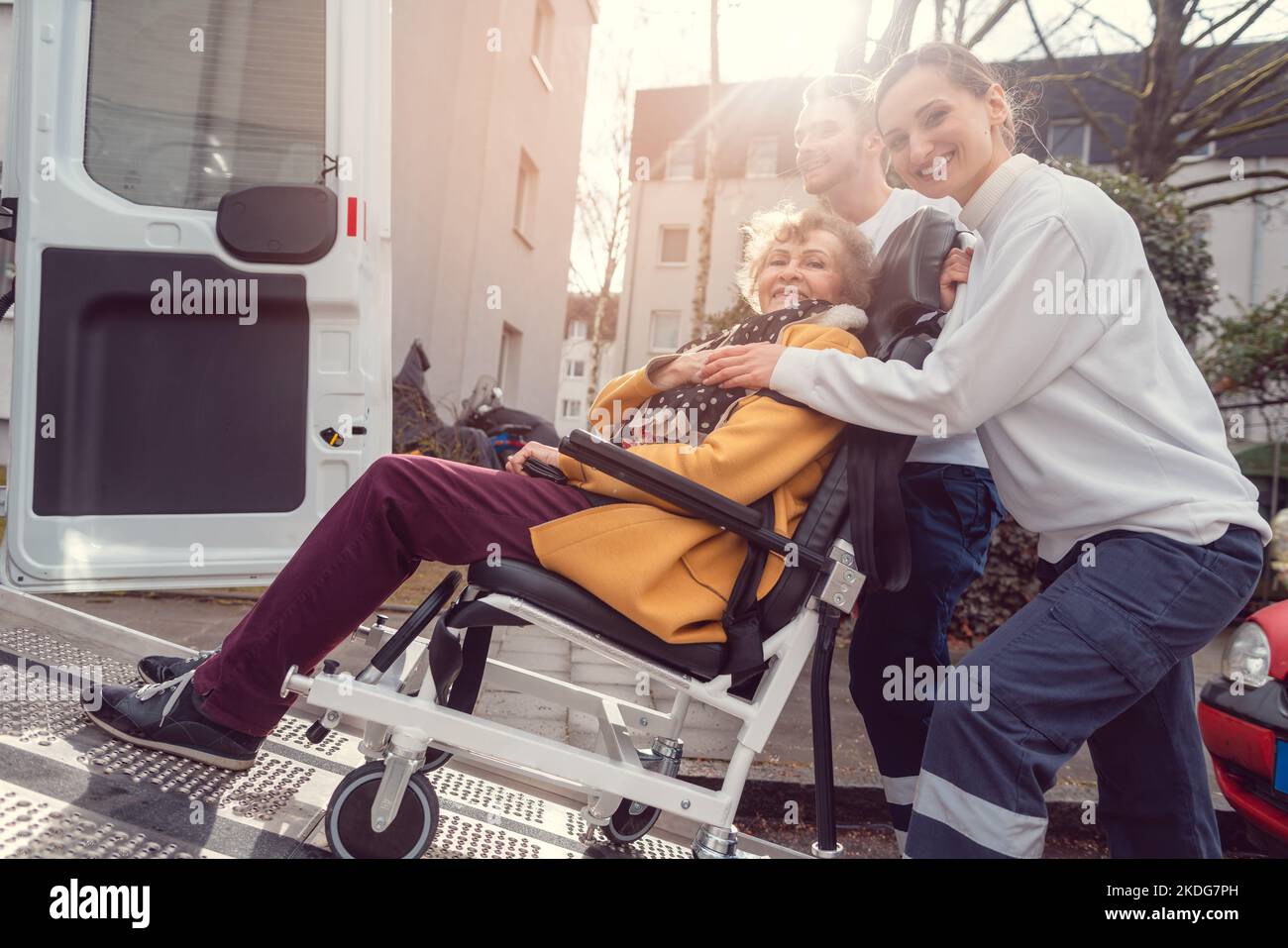 Donna anziana in sedia a rotelle che viene ritirata dal servizio di trasporto Foto Stock